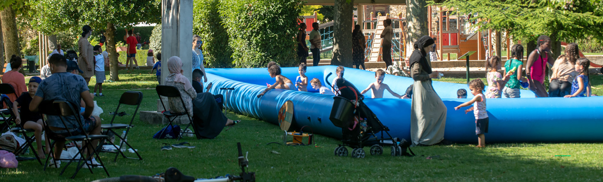 Visuel décoratif représentant des enfants jouant dans l'herbe dans un parc d'Asnières-sur-Seine avec leurs parents.