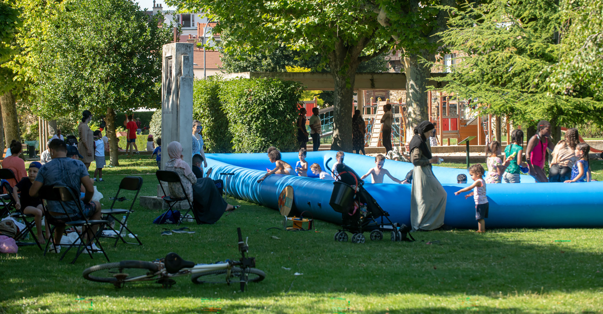 Visuel décoratif représentant des enfants jouant dans l'herbe dans un parc d'Asnières-sur-Seine avec leurs parents.