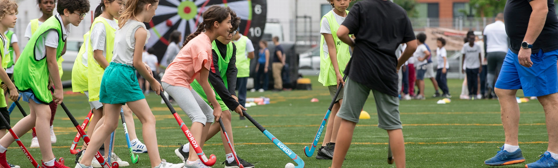 Photo décorative représentant des jeunes enfants jouant au hockey sur gazon.