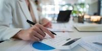 Visuel décoratif représentant une personne faisant des calculs sur une calculatrice.
