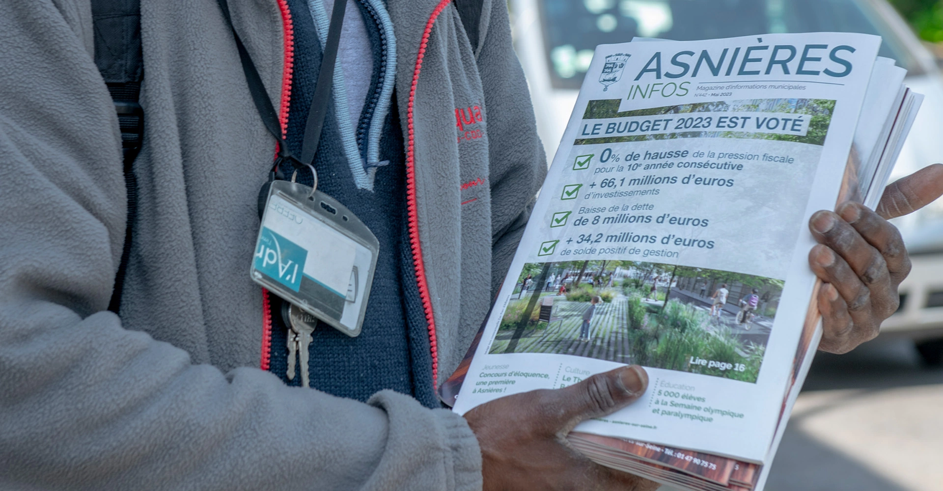 Visuel décoratif représentant une personne en train de tenir un paquet de magazines municipaux d'Asnières-sur-Seine.