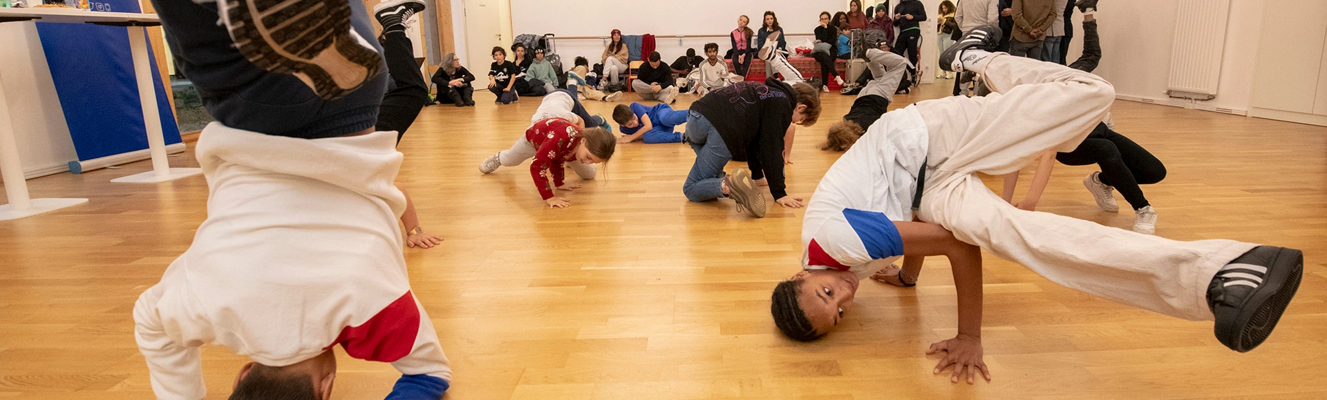 Visuel décoratif représentant des jeunes en train de faire du brek-danse tandis que d'autres regardent.