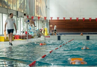 Une photo d'un maître nageur donnant des cours de natations à des enfants