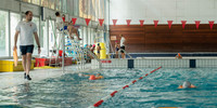 Une photo d'un maître nageur donnant des cours de natations à des enfants