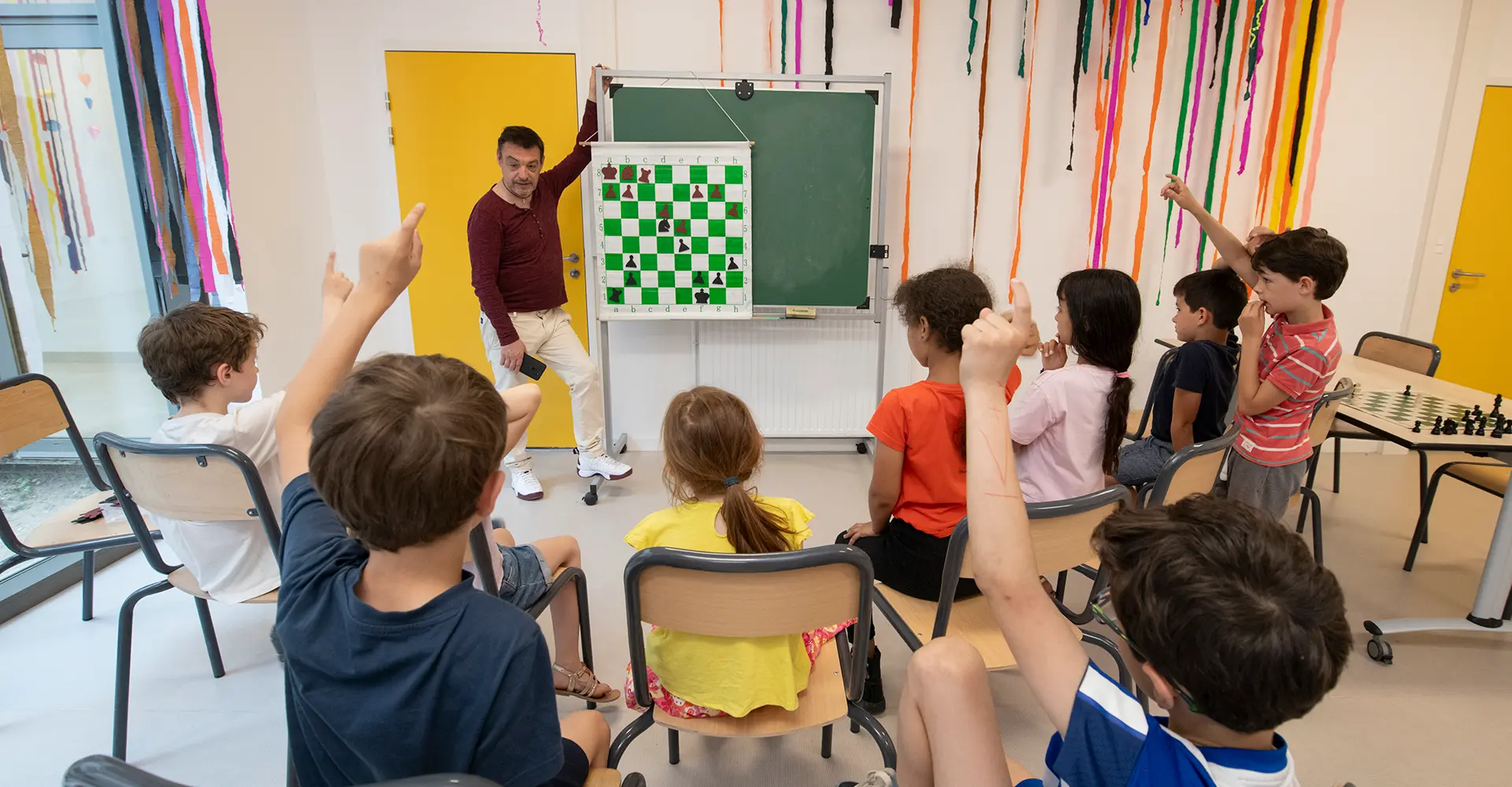 Visuel décoratif représentant des enfants participant à une activité périscolaire autour des échecs.